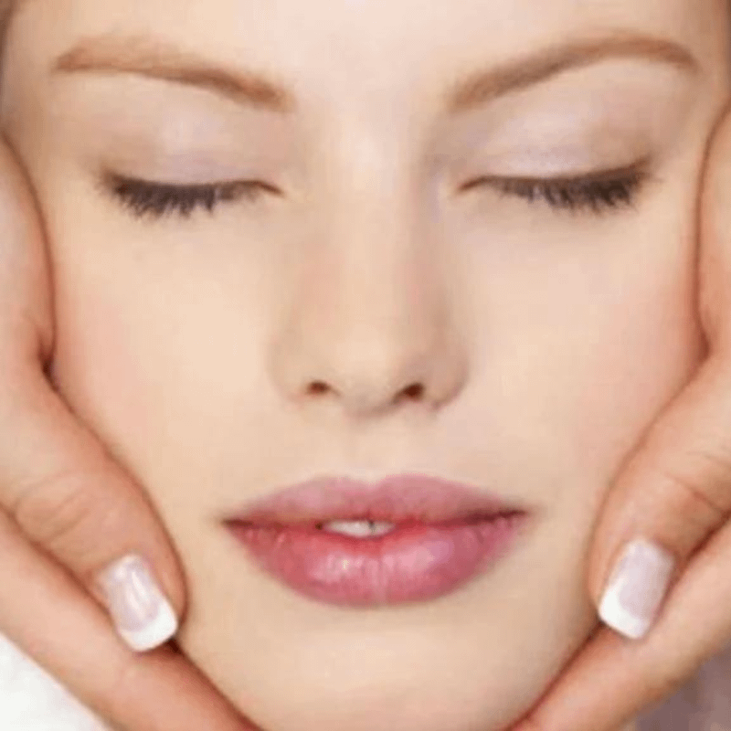 Close-up of a client’s face with the therapist’s hands cupping their jawline during an Access Energetic Facelift session, enhancing radiance and relaxation.
