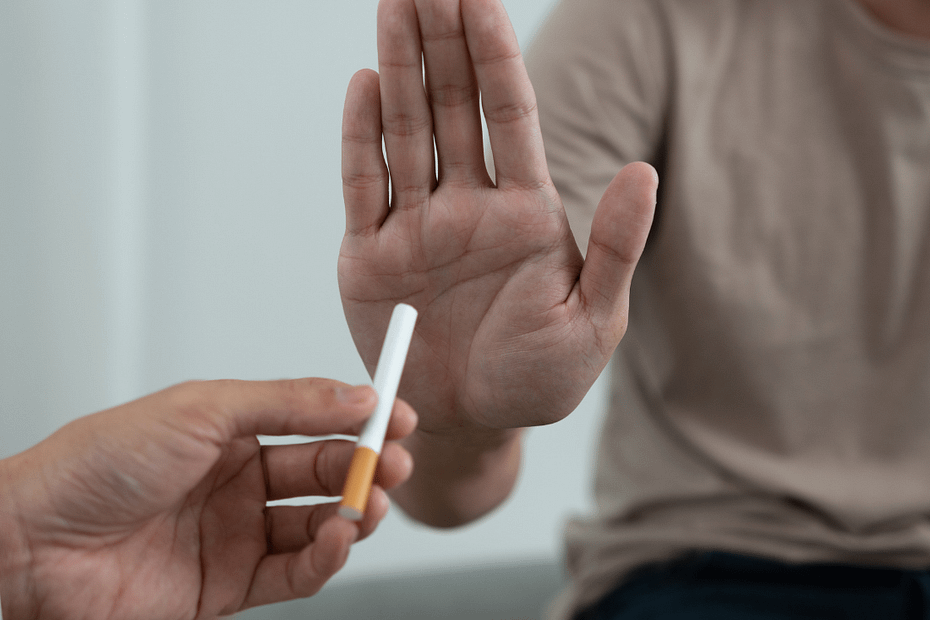 Close-up of a person holding up a hand to decline a cigarette being offered, symbolizing the decision to quit smoking.