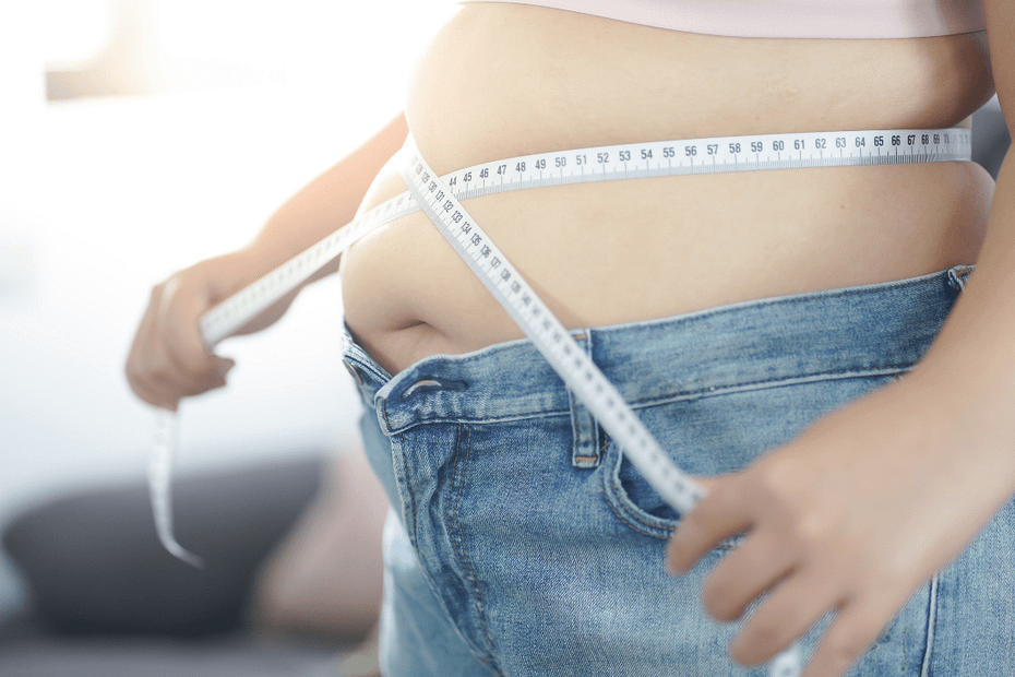 Close-up of a person measuring their waist with a tape measure, highlighting a focus on weight management and progress.